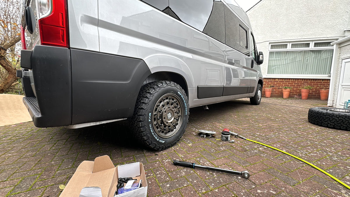 A new set of Rogue wheels going onto a silver Ducato-based van on a driveway, the torque bar and the fitting kit laid out