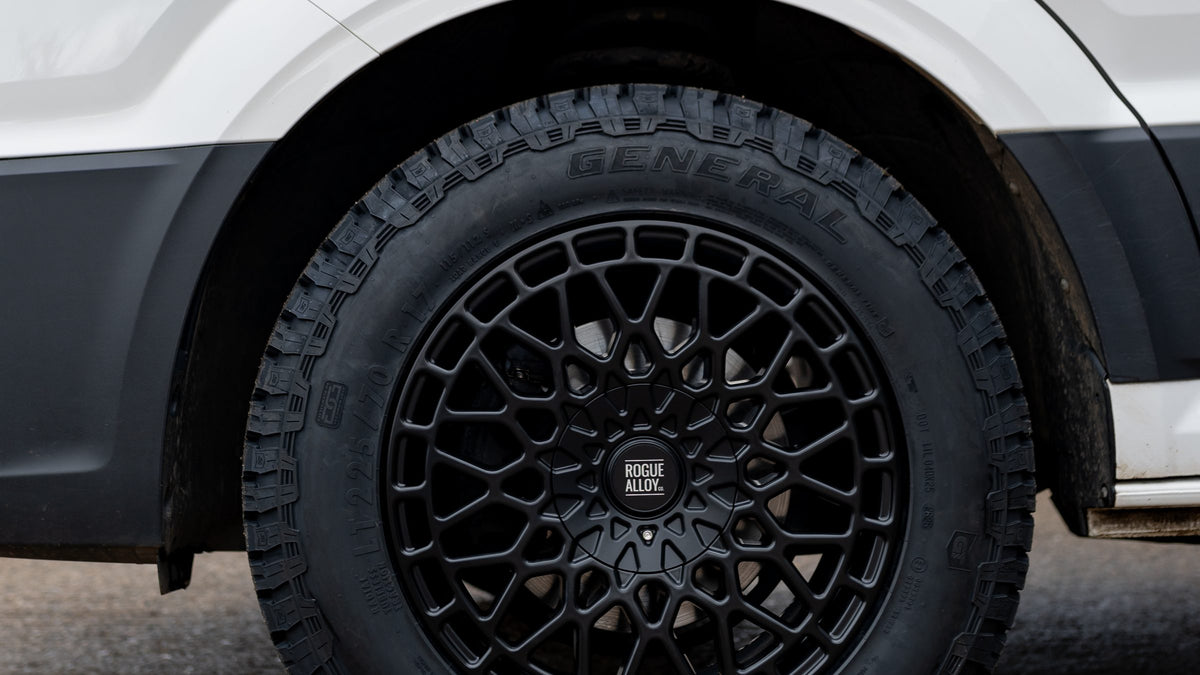 A black Rogue mesh wheel and General Grabber tyre in the front arch of a white Volkswagen Crafter