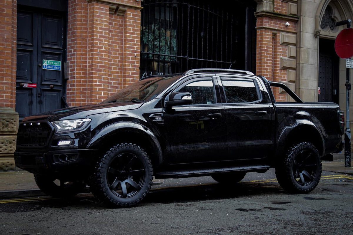 A black Ford Ranger on black Rogue wheels and mud-terrain tyres outside a city building